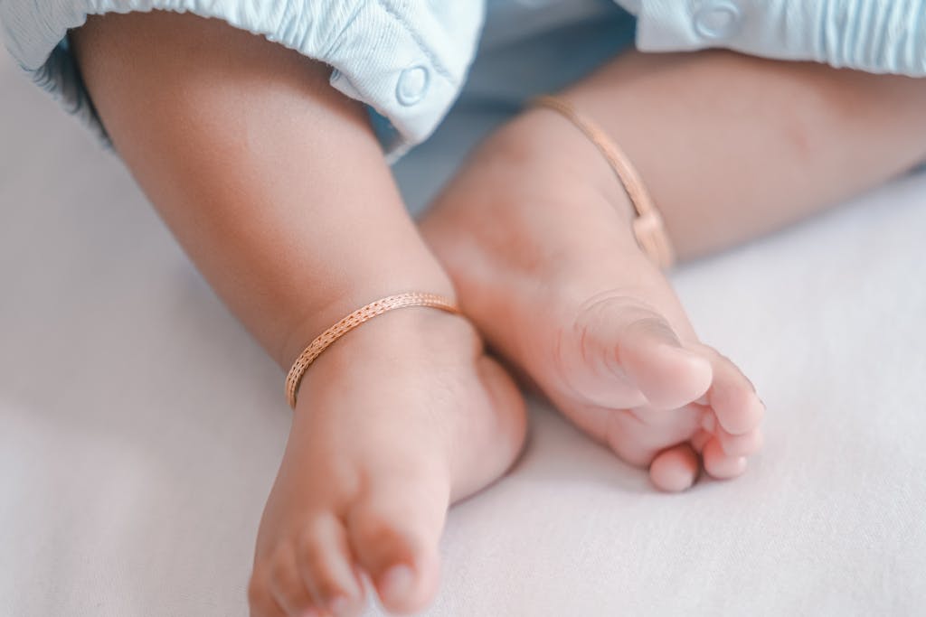 Close-up of a baby's feet adorned with delicate gold anklets, showcasing tenderness and innocence.