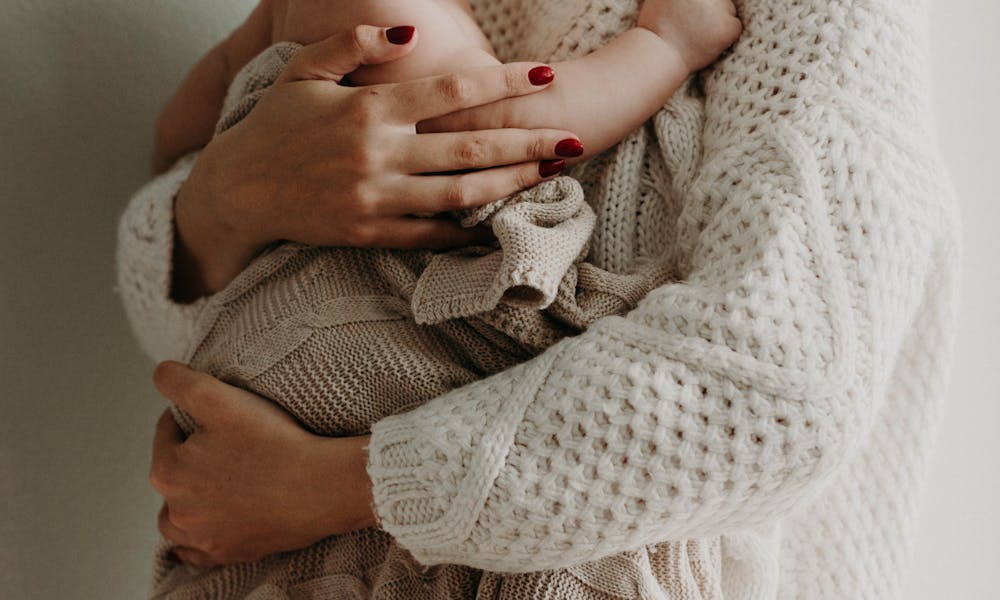 Close-up of a mother holding her baby in warm knitwear, conveying love and togetherness.