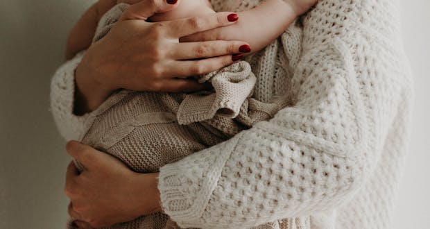 Close-up of a mother holding her baby in warm knitwear, conveying love and togetherness.