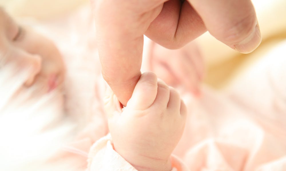 Heartwarming close-up of a baby holding a parent's finger, symbolizing love and connection.